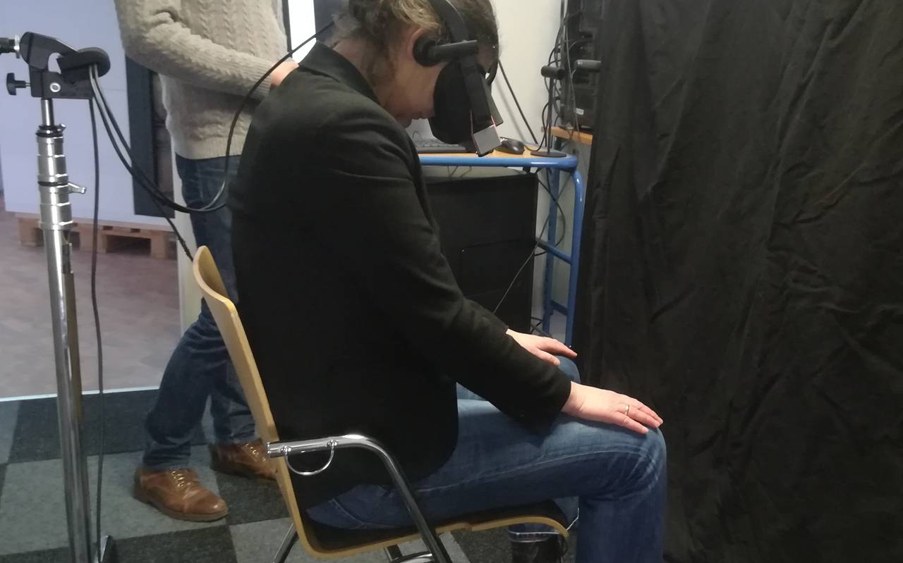 Junge Frau sitzt mit gesenktem Kopf und trägt eine dunkle VR-Brille.