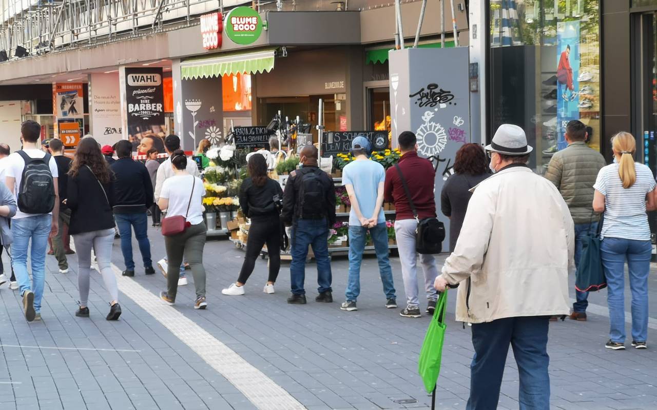 Menschen warten vor dem Saturn auf dem Westenhellweg in Dortmund auf den Einlass.