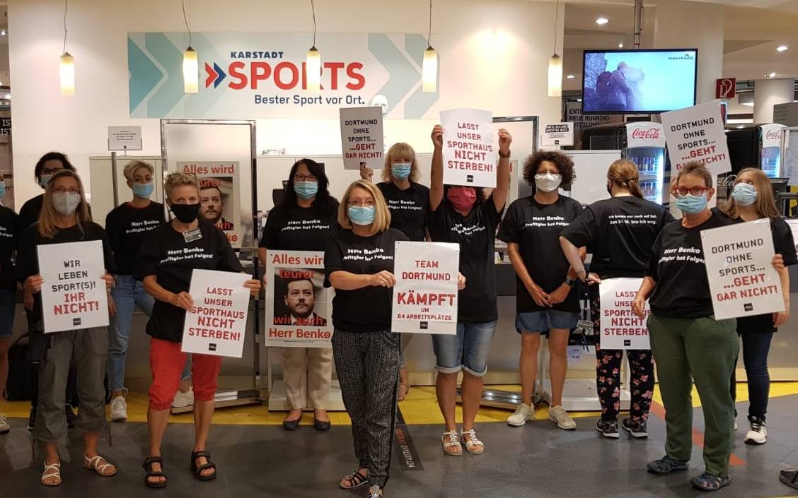 Karstadt-Sports Mitarbeiter zeigen Tshirts und Plakate, die auf ihre kommende Arbeitslosigkeit aufmerksam machen sollen.