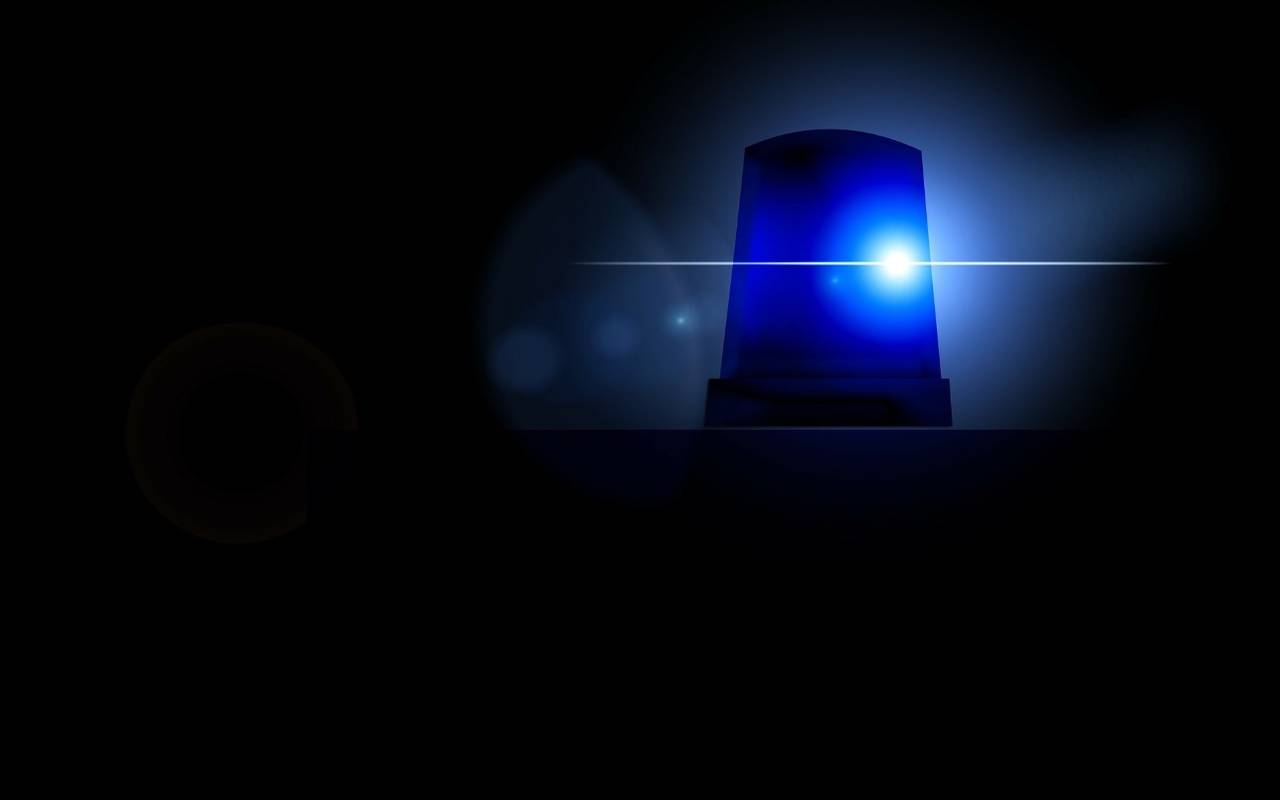 Ein Blaulicht eines Polizeiwagens scheint. Das Bild drum herum ist schwarz