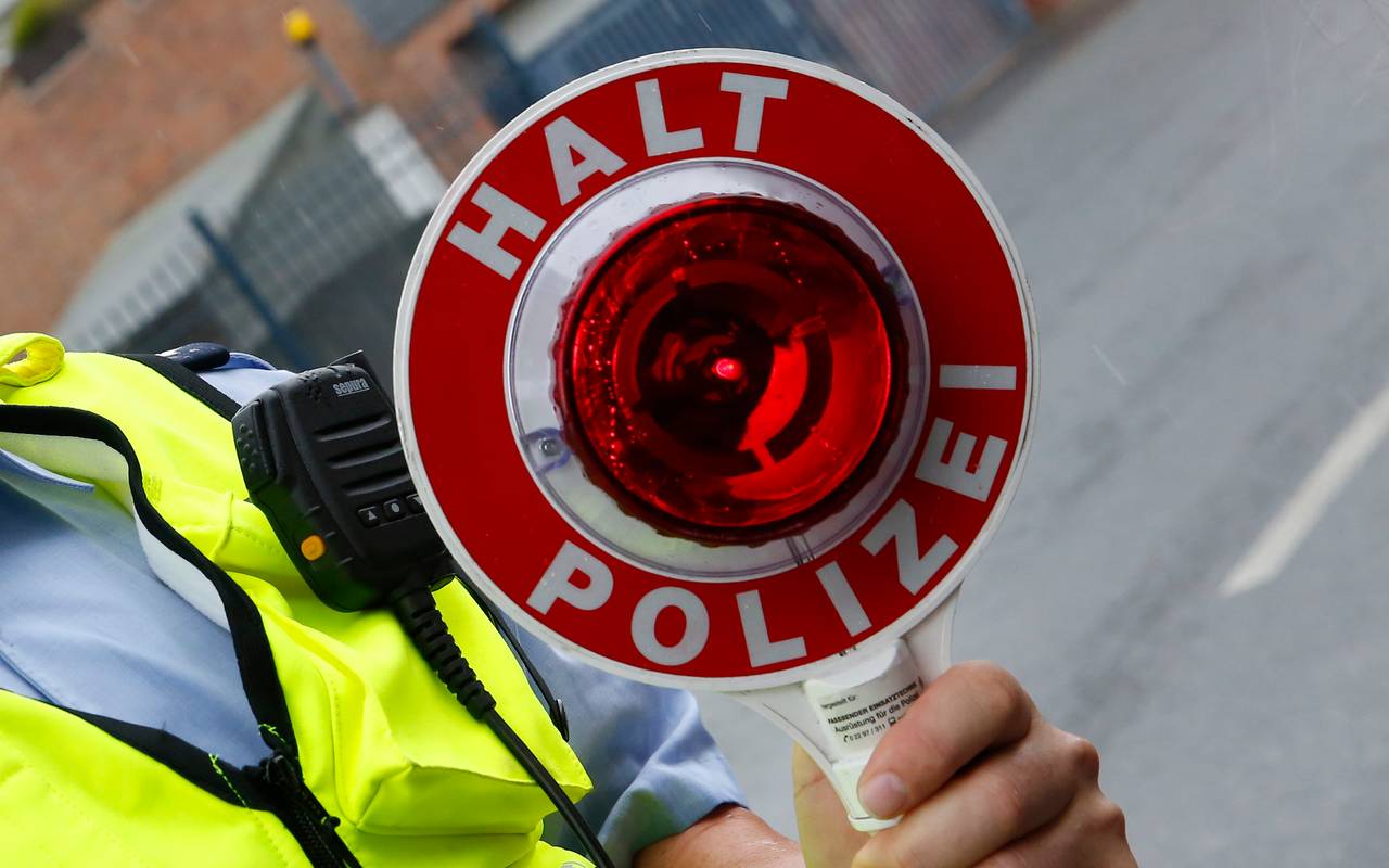 Polizeibeamter mit "Halt Polizei"-Kelle in der Hand