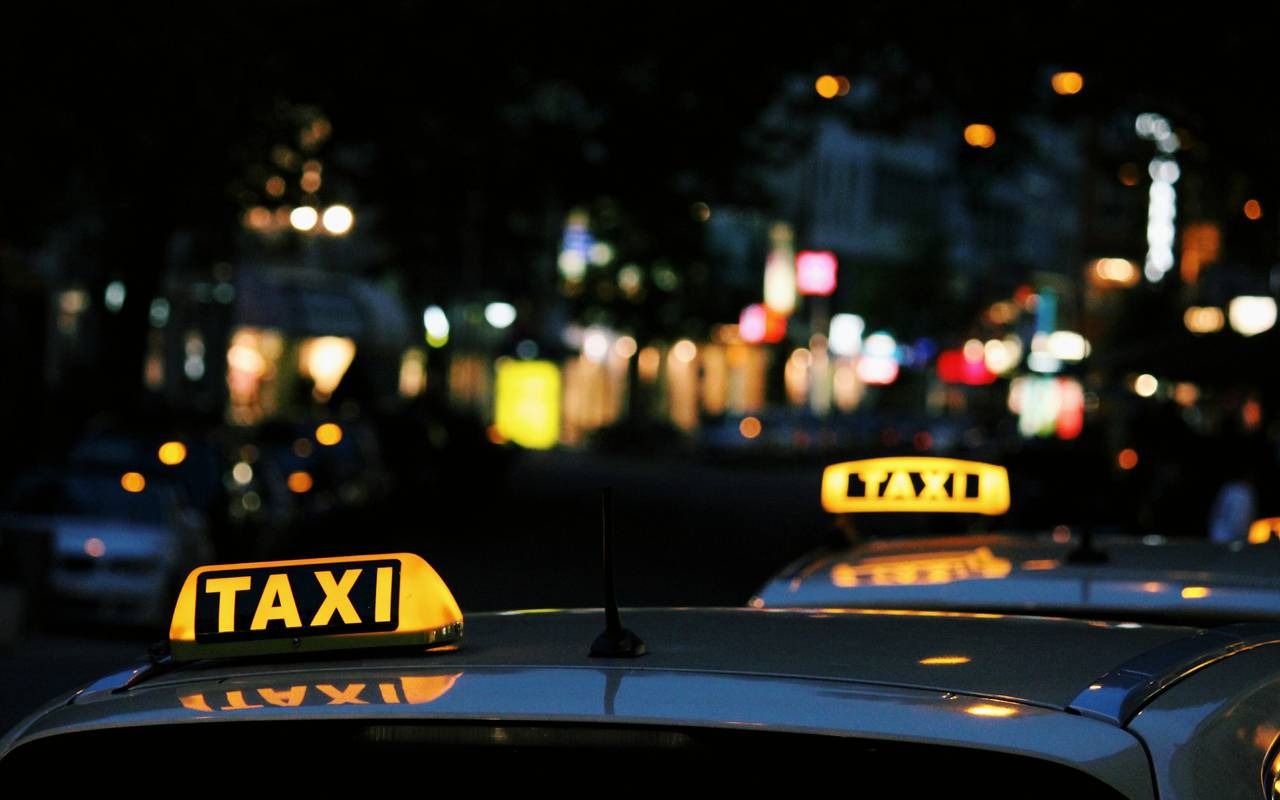Taxi-Schilder auf Fahrzeugdächern bei Nacht