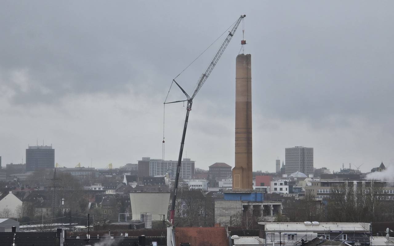 Abrisskran baut den Schornstein auf dem alten RWE-Gelände langsam ab.