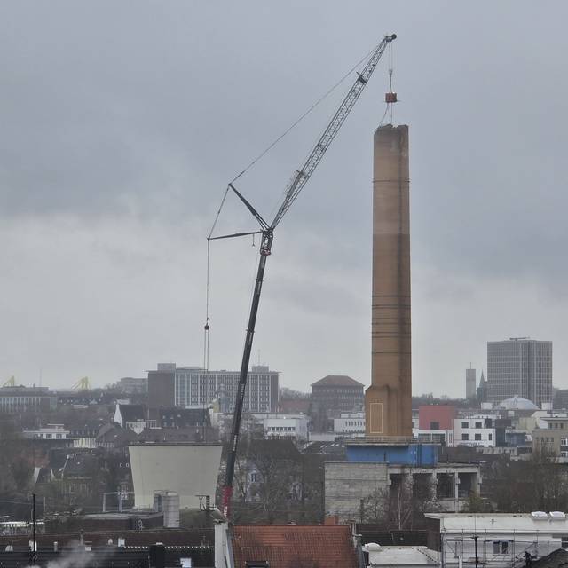 Abrisskran baut den Schornstein auf dem alten RWE-Gelände langsam ab.