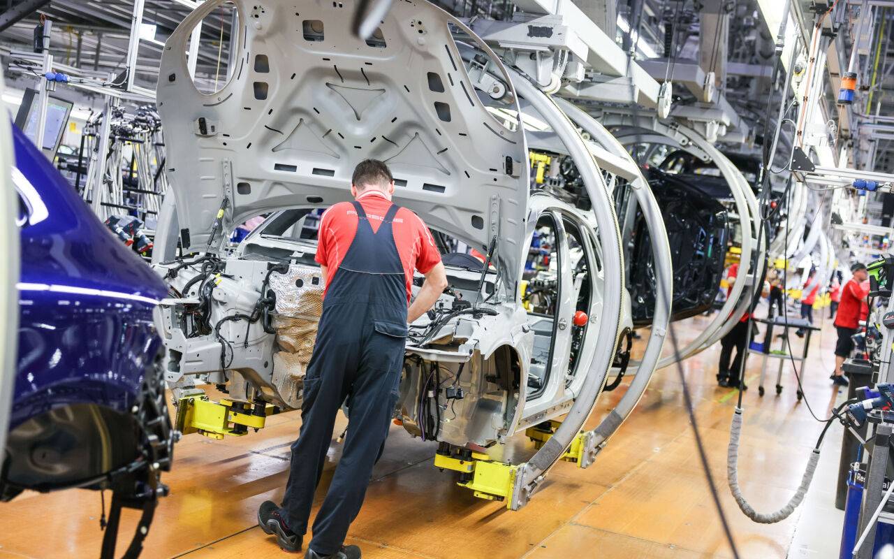 Ein Mitarbeiter montiert einen Porsche Macan in einem Werk.