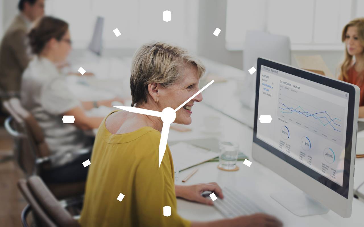 Frauen im Büro am PC mit einer Uhr im Vordergrund