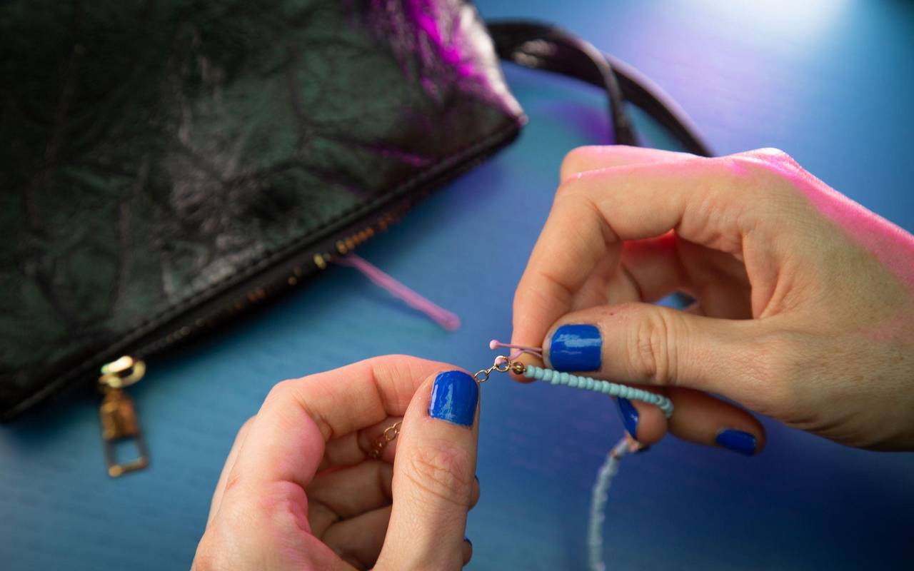 Frau fädelt eine Haarnadel durch das Kettenglied eines Armbands
