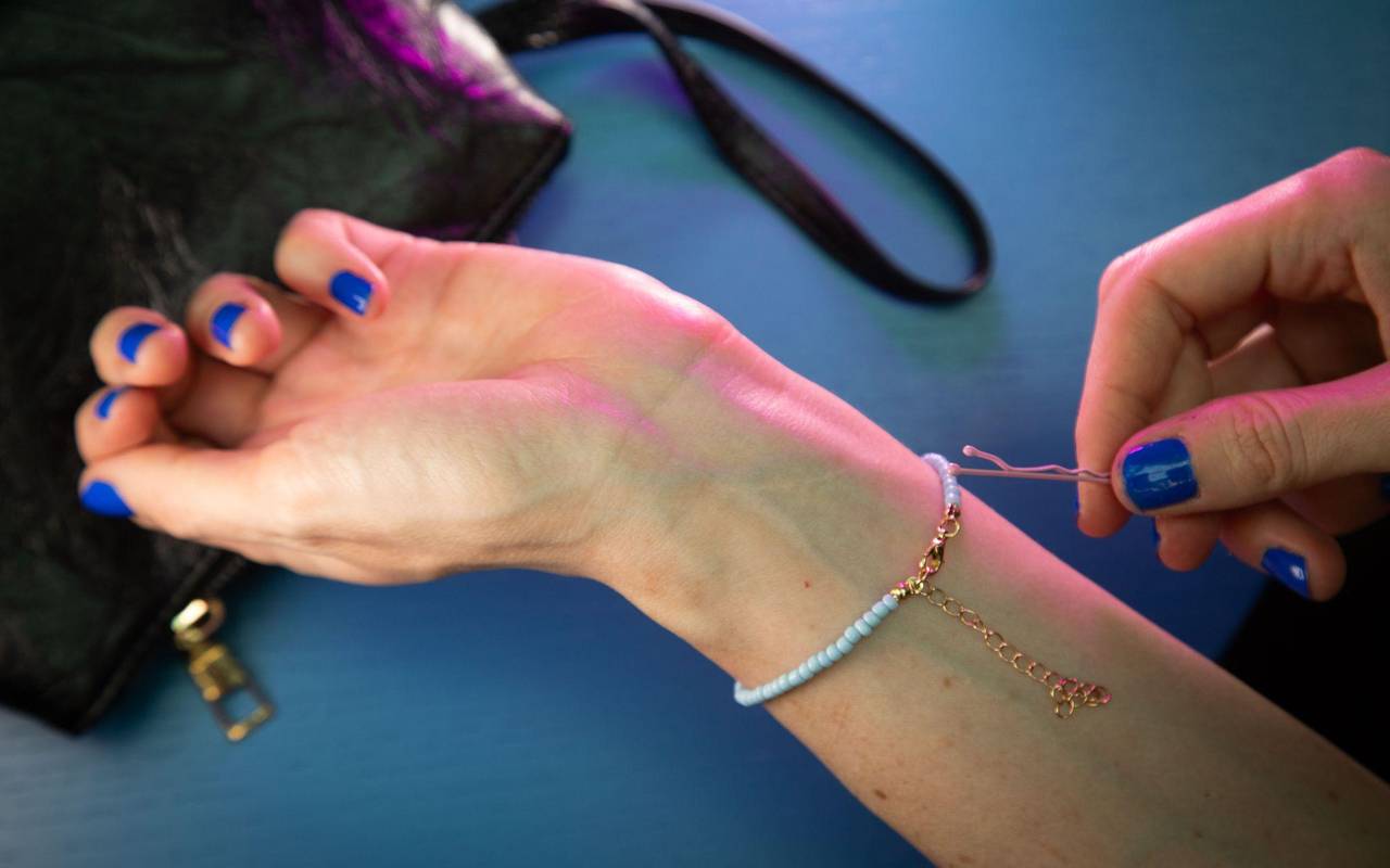 Frau legt Armband mit Hilfe einer Haarnadel an