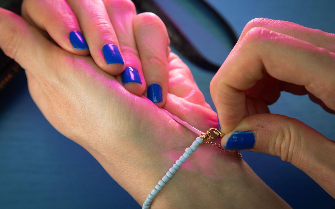 Frau legt Armband mit Hilfe einer Haarnadel an