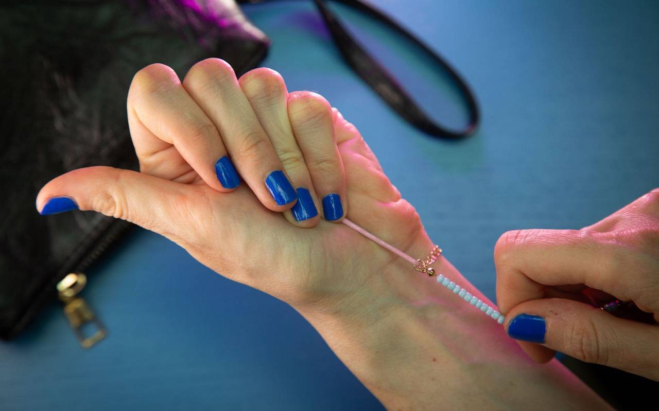 Frau legt Armband mit Hilfe einer Haarnadel an