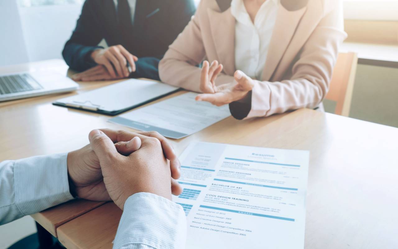 Ein Mann sitzt gegenüber von zwei Personen bei einem Bewerbungsgespräch