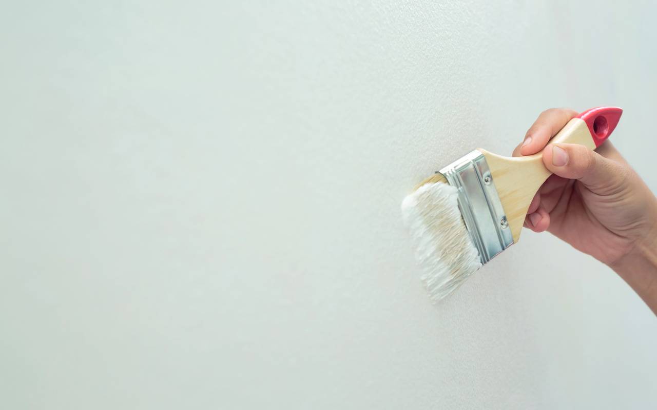 Eine Wand wird mit einem Pinsel Mint grün gestrichen