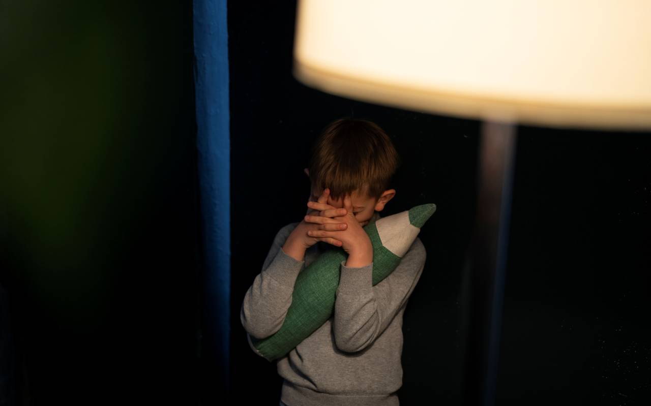 Kind hält sich de Augen mit beiden Händen zu