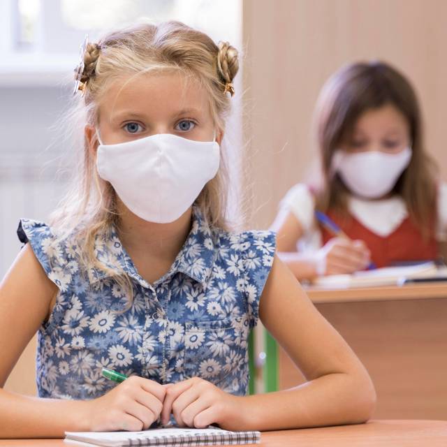 Schülerinnen tragen Masken im Klassenzimmer