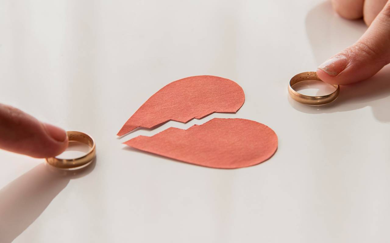 Ein gebrochenes Herz aus Papier und zwei Eheringe