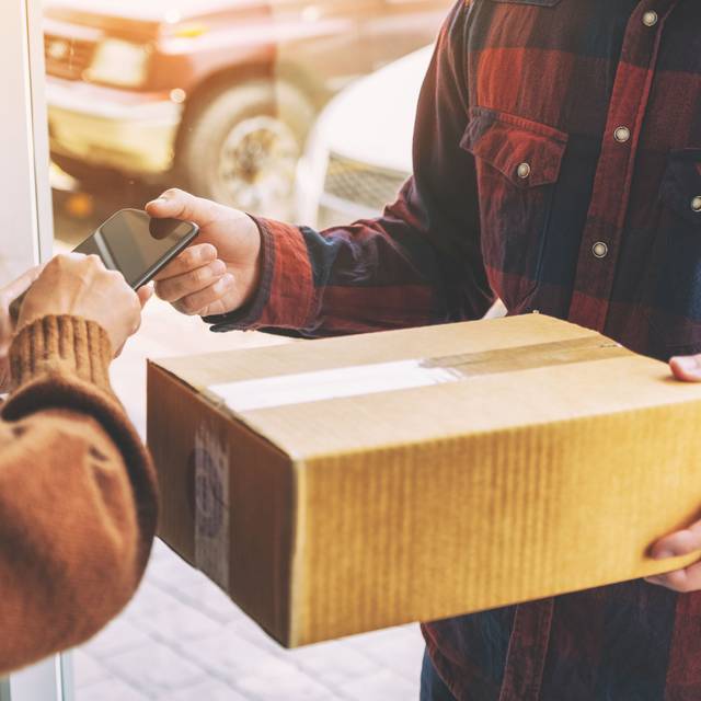 Paketbote übergibt an der Haustür ein Paket