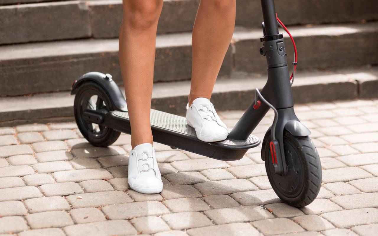 Frau steht auf einem E-Scooter