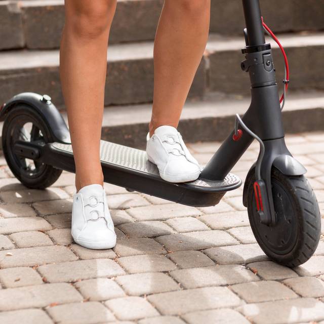 Frau steht auf einem E-Scooter