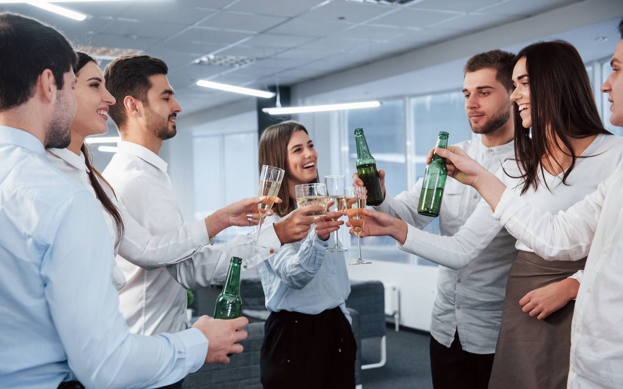 Mehrere Kollegen stoßen im Büro mit Wein an