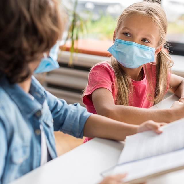 Zwei Schüler tragen eine Maske in der Klasse