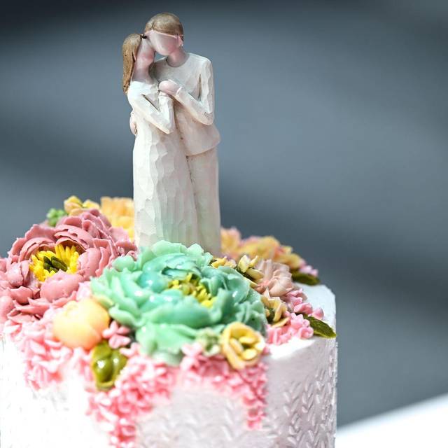 Die Figur eines Brautpaares steht auf einer Hochzeitstorte