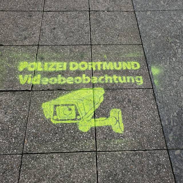 Polizei Dortmund macht mit Spray-Logos auf der Straße auf die Videoüberwachung aufmerksam.