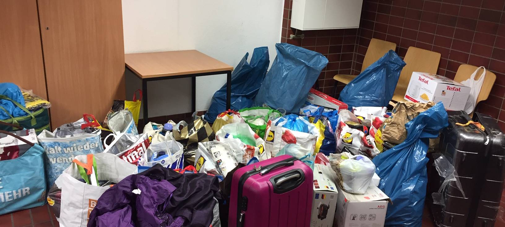 Einkaufstaschen, die mit allerhand Gegenständen gefüllt sind : von Kosmetikartikeln über Süßwaren bis hin zu teils hochwertigem Werkzeug