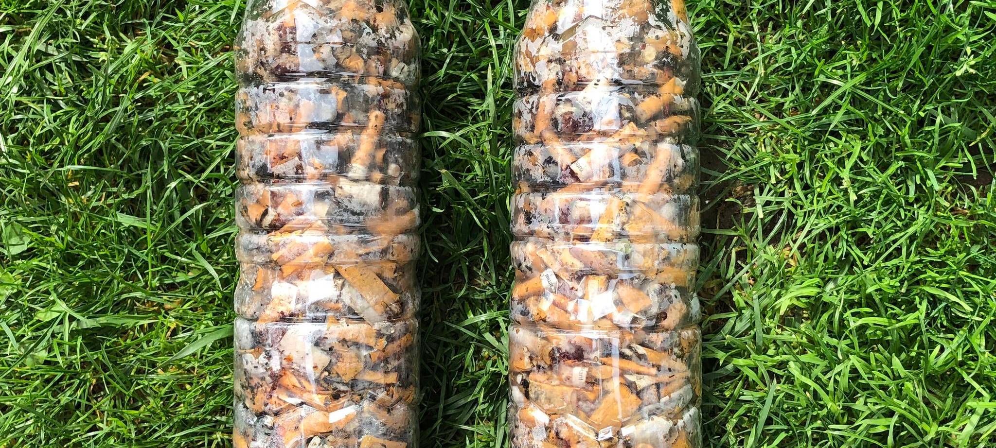 Zwei Plastikflaschen gefüllt mir Zigarettenkippen