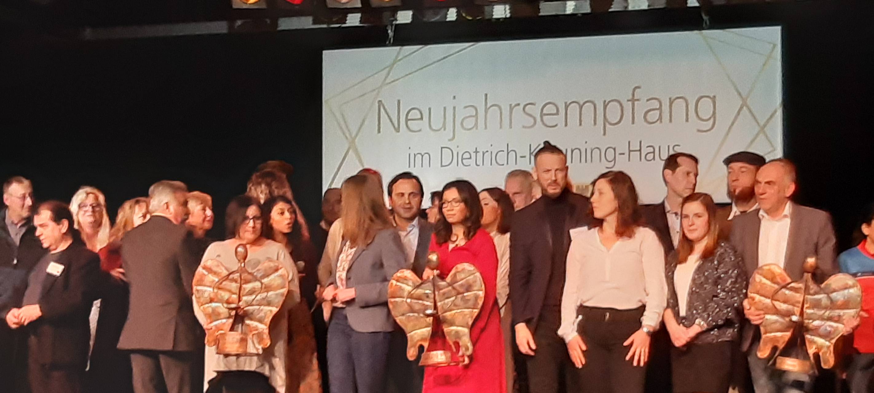 Mehrere Personen auf einer Bühne lächeln in die Kamera