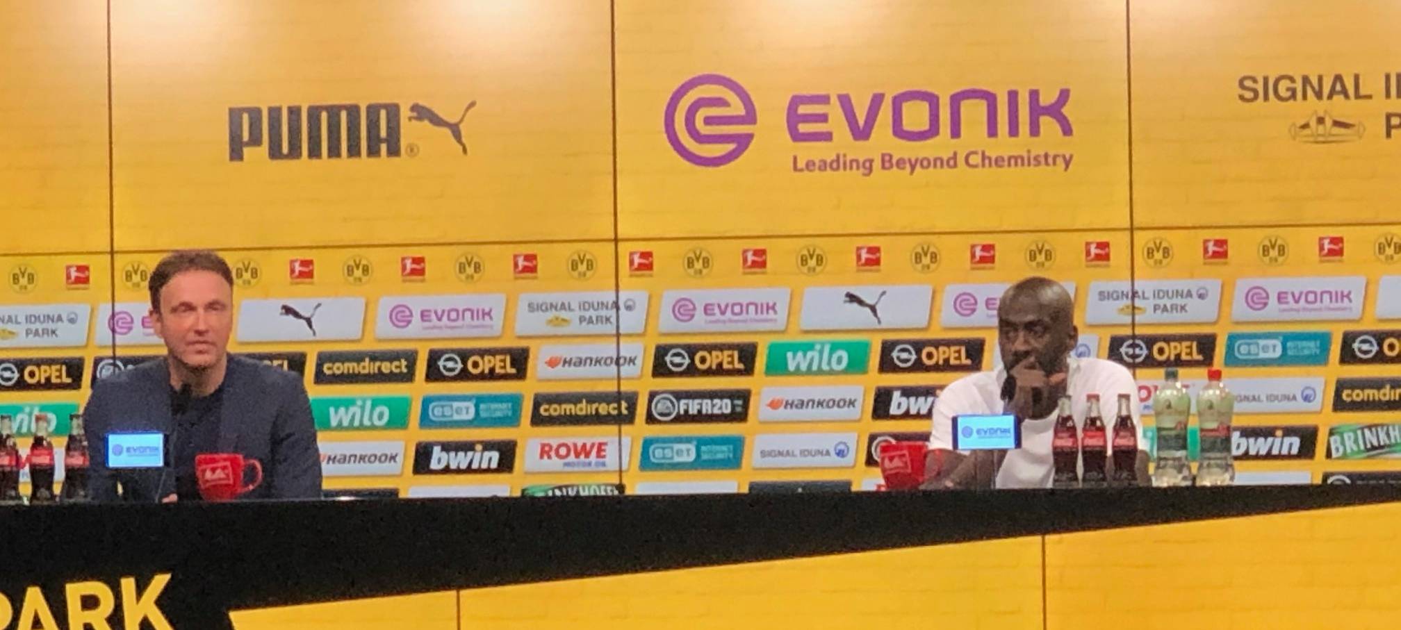 Zwei Männer sitzen hinter einem Podium.