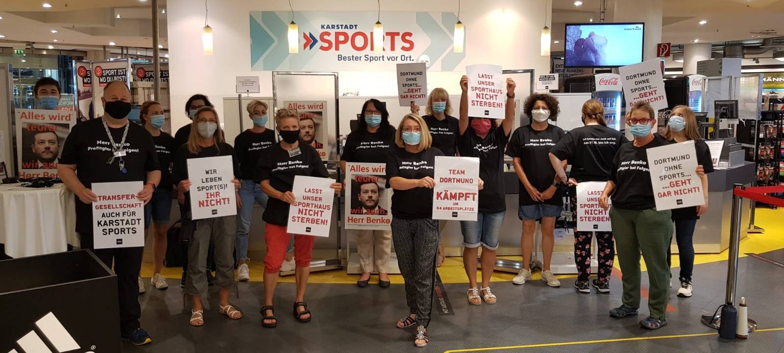 Karstadt-Sports Mitarbeiter zeigen Tshirts und Plakate, die auf ihre kommende Arbeitslosigkeit aufmerksam machen sollen.
