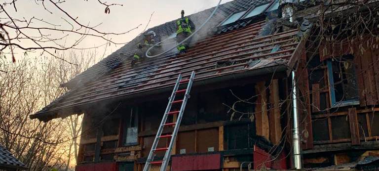 Einsatzkräfte löschen auf dem Dach des Hauses