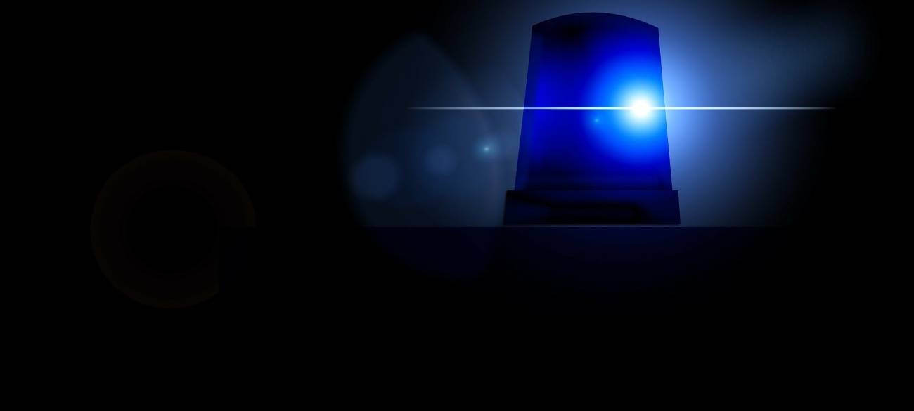 Ein Blaulicht eines Polizeiwagens scheint. Das Bild drum herum ist schwarz