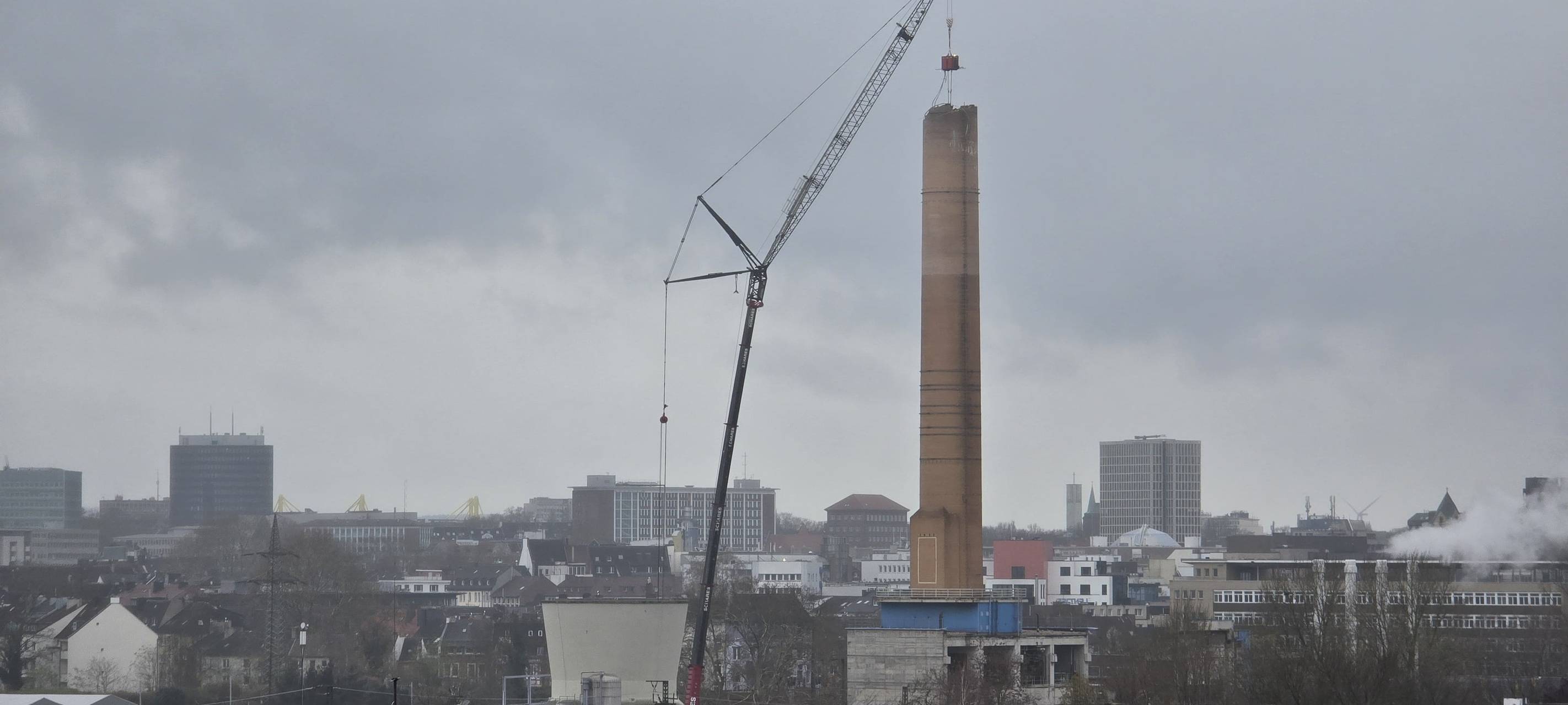 Abrisskran baut den Schornstein auf dem alten RWE-Gelände langsam ab.