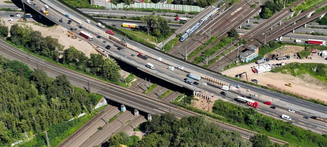 Aus der Vogelperspektive ist das Autobahnkreuz Kaiserberg in Duisburg mitsamt Bahnübergang zu sehen.