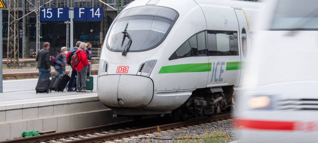 Menschen steigen mit Koffern in einen ICE-Zug der Deutschen Bahn ein.