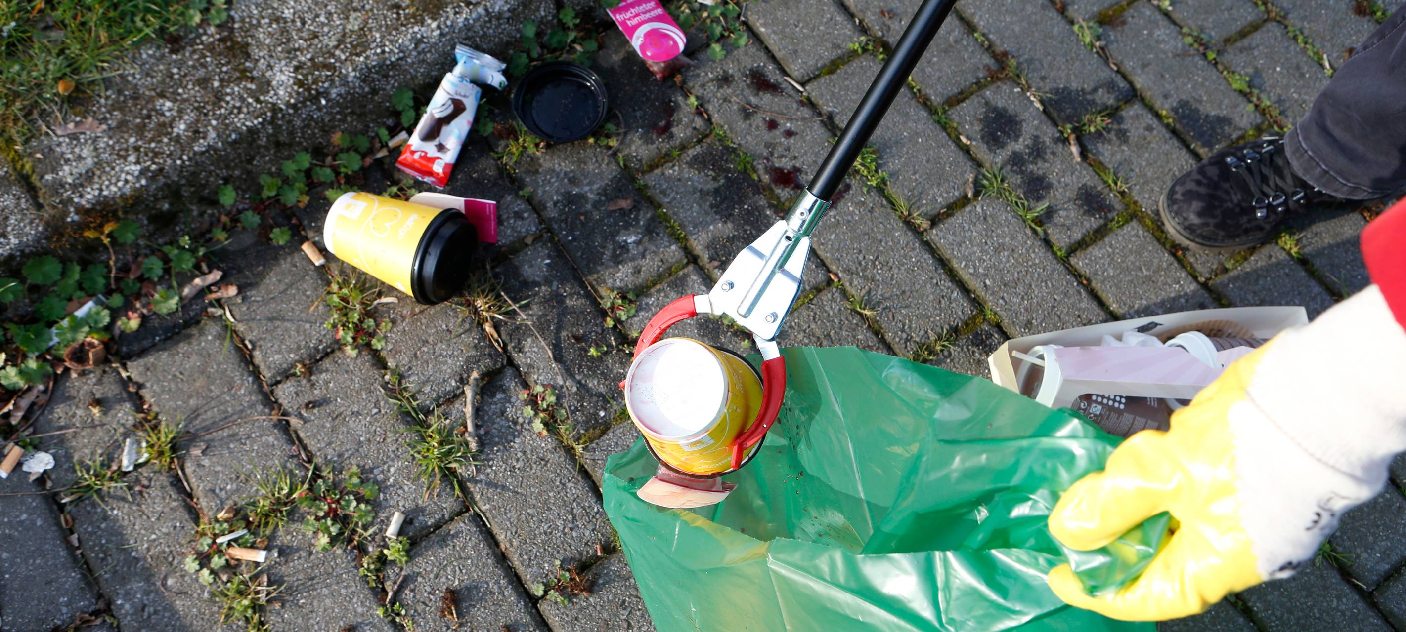 Ein Bild mit einer Müllzange, die Müll von der Straße aufhebt.