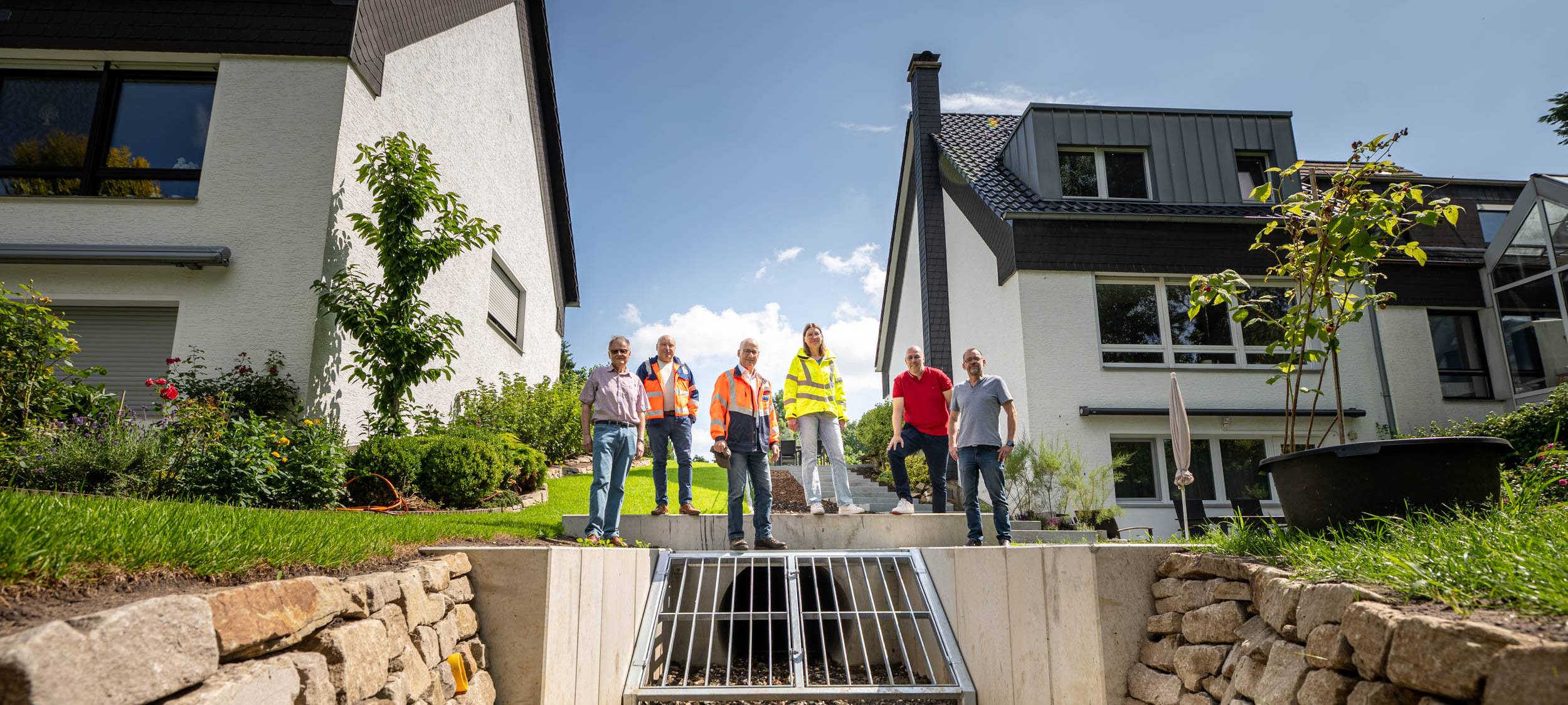 Anwohner und Stadtvertreter präsentieren den neuen Gewässerdurchlass, der künftig vor Überflutungen schützt.