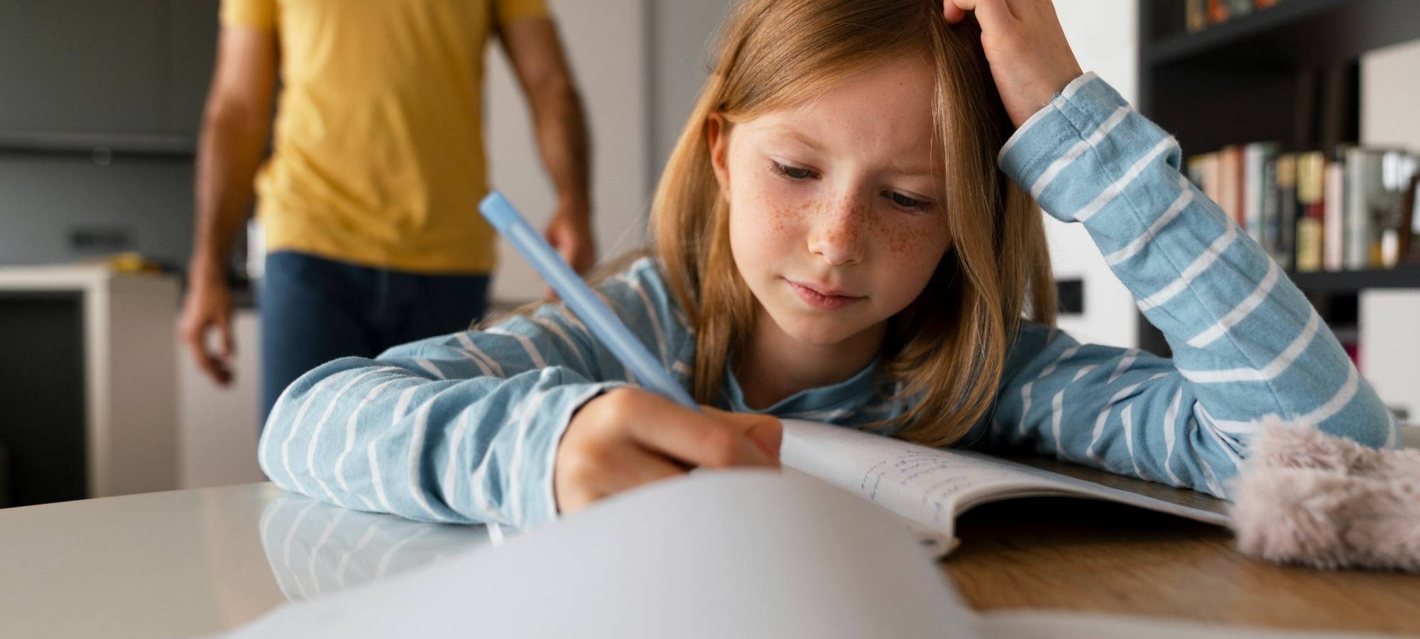 Junges Mädchen sitzt am Tisch und macht Hausaufgaben.