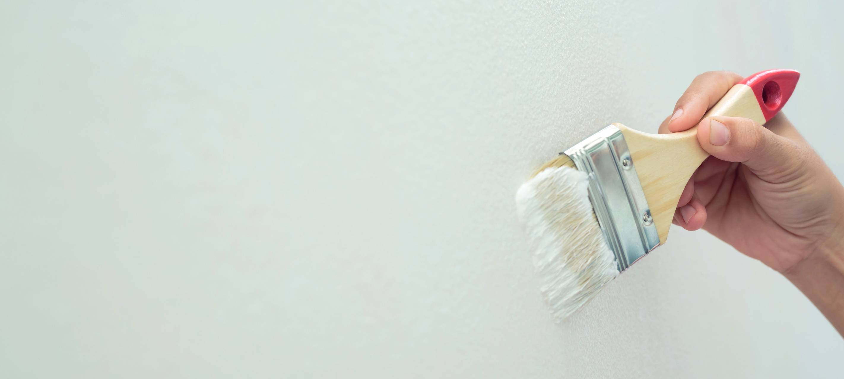 Eine Wand wird mit einem Pinsel Mint grün gestrichen