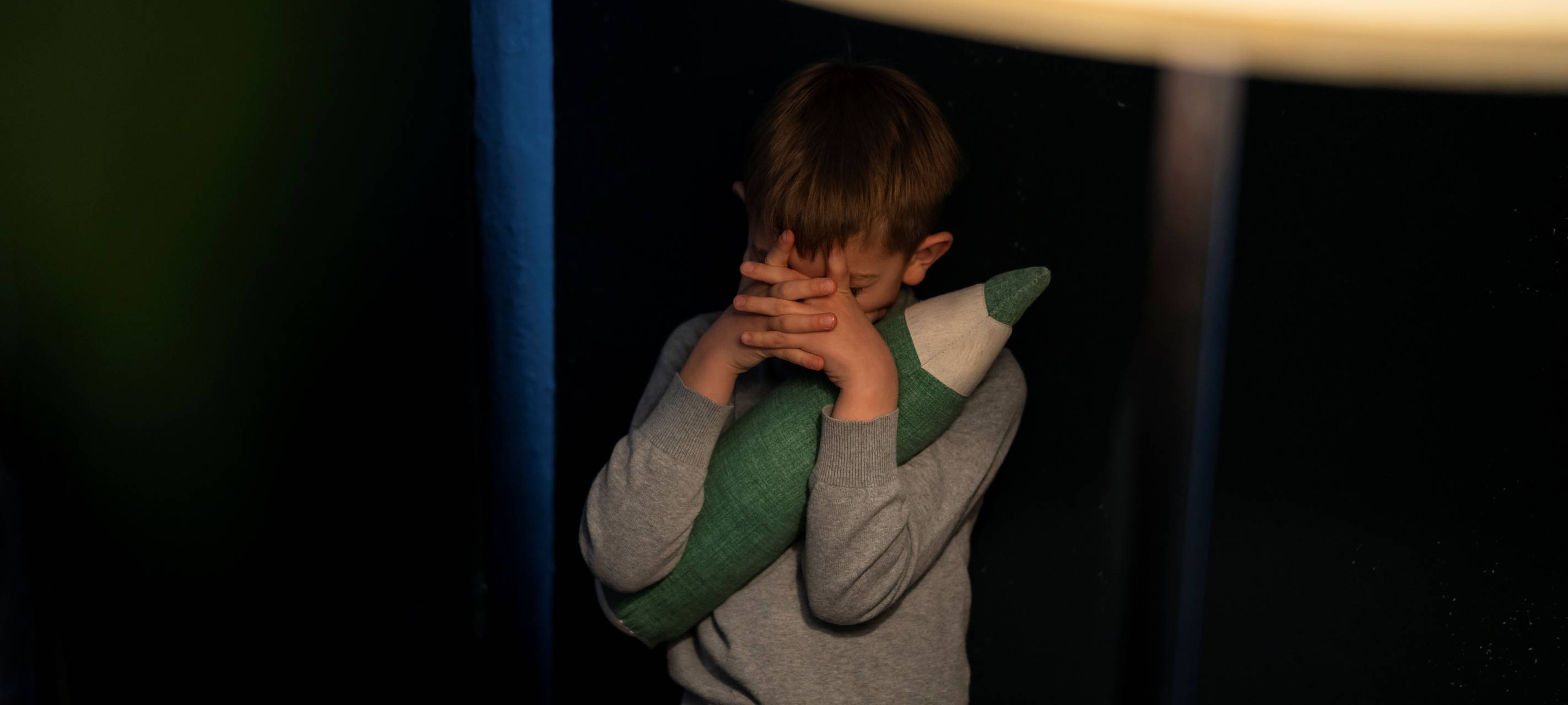 Kind hält sich de Augen mit beiden Händen zu