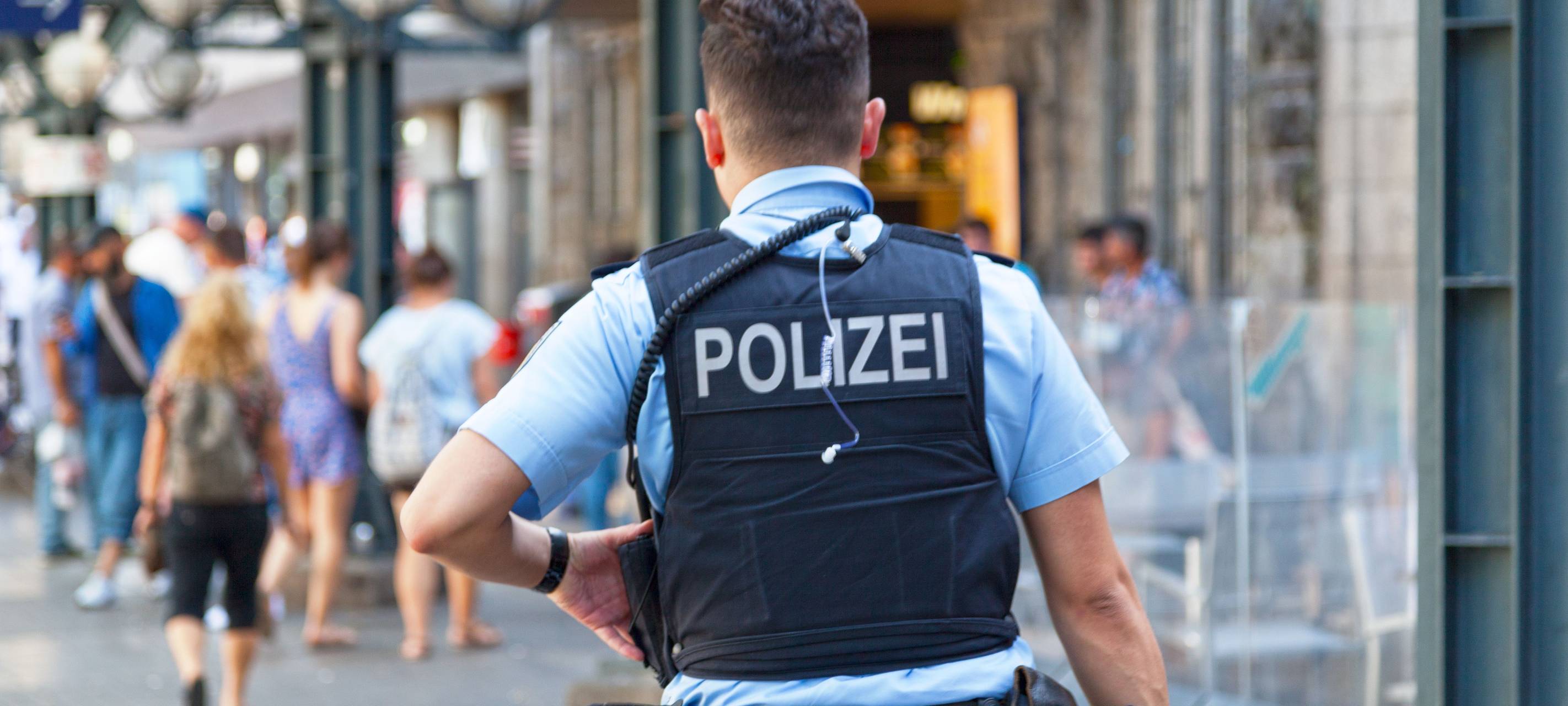 Polizist mit Polizeiweste von hinten
