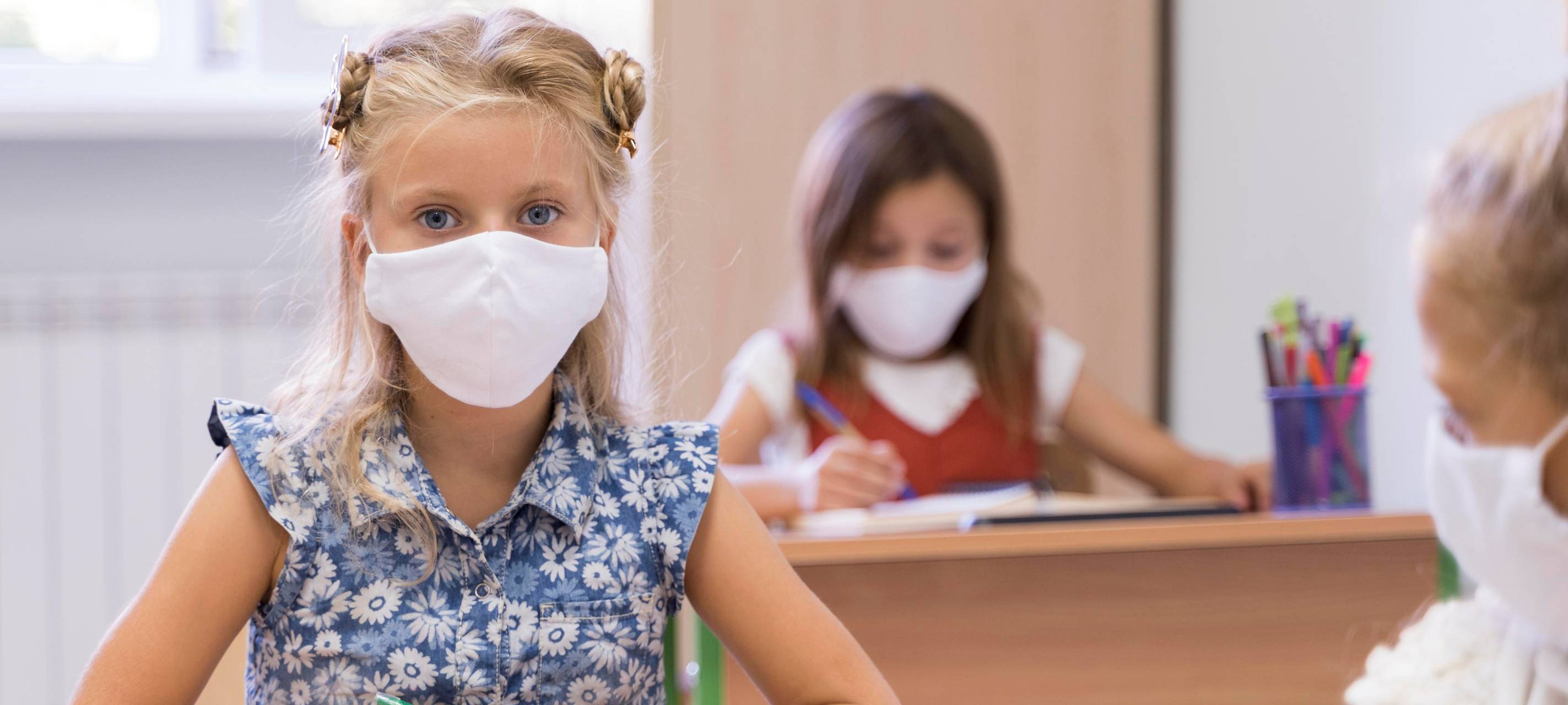 Schülerinnen tragen Masken im Klassenzimmer