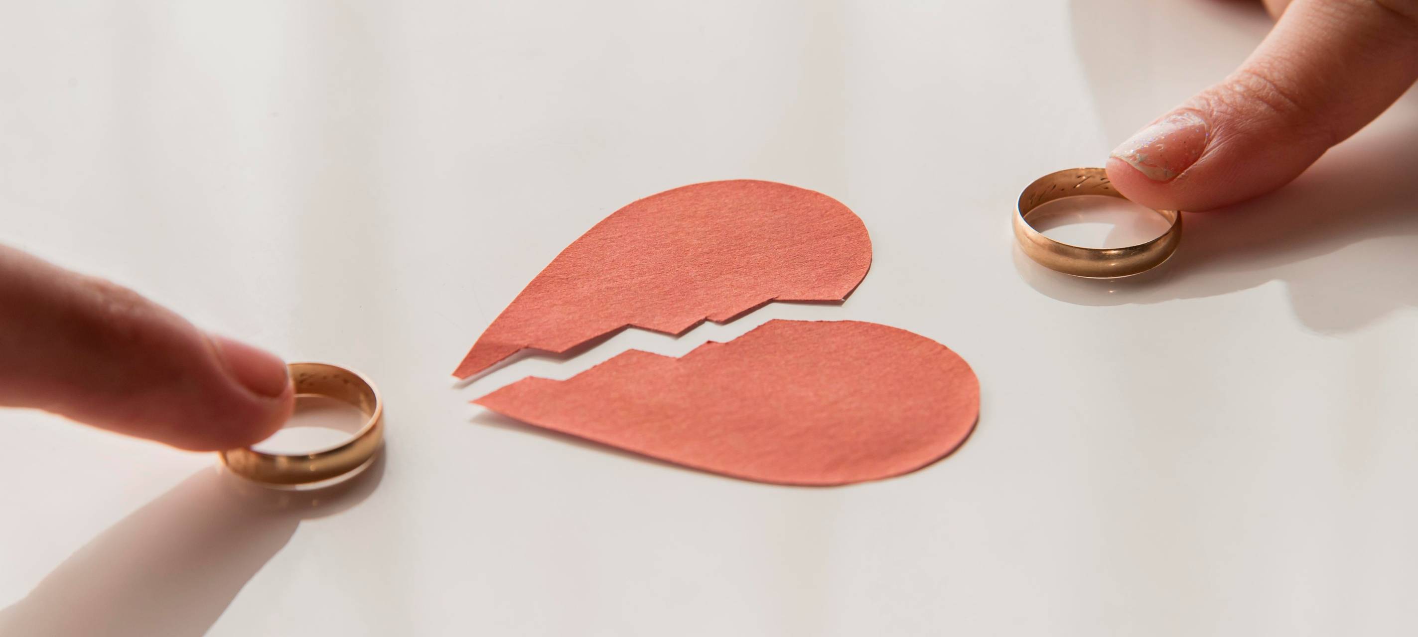 Ein gebrochenes Herz aus Papier und zwei Eheringe