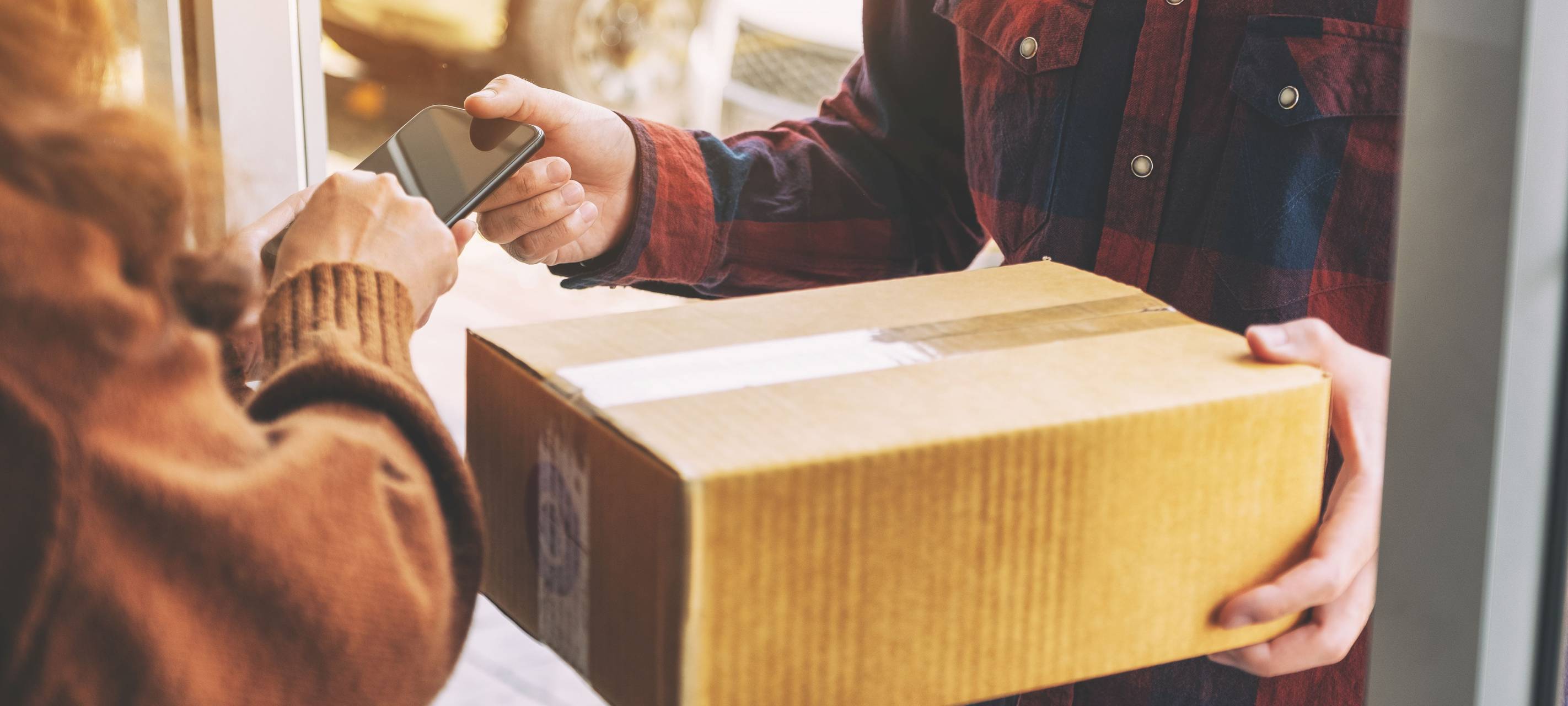 Paketbote übergibt an der Haustür ein Paket