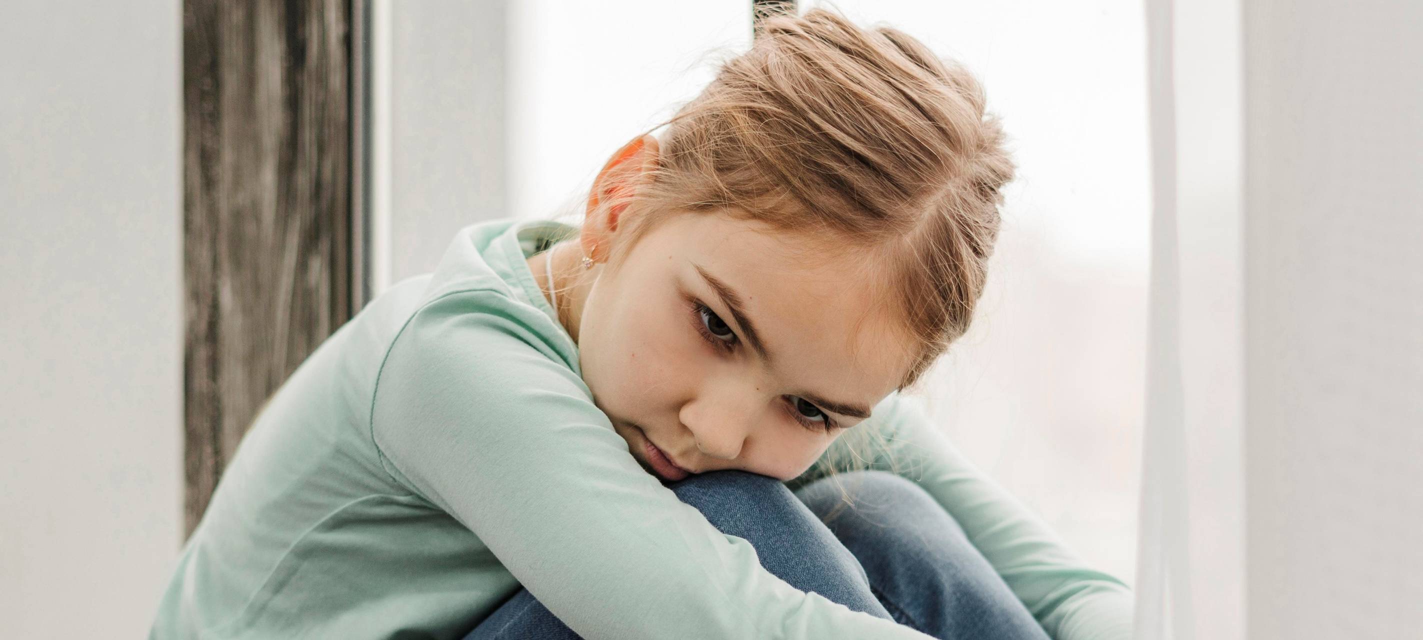 Kind sitzt traurig am Boden