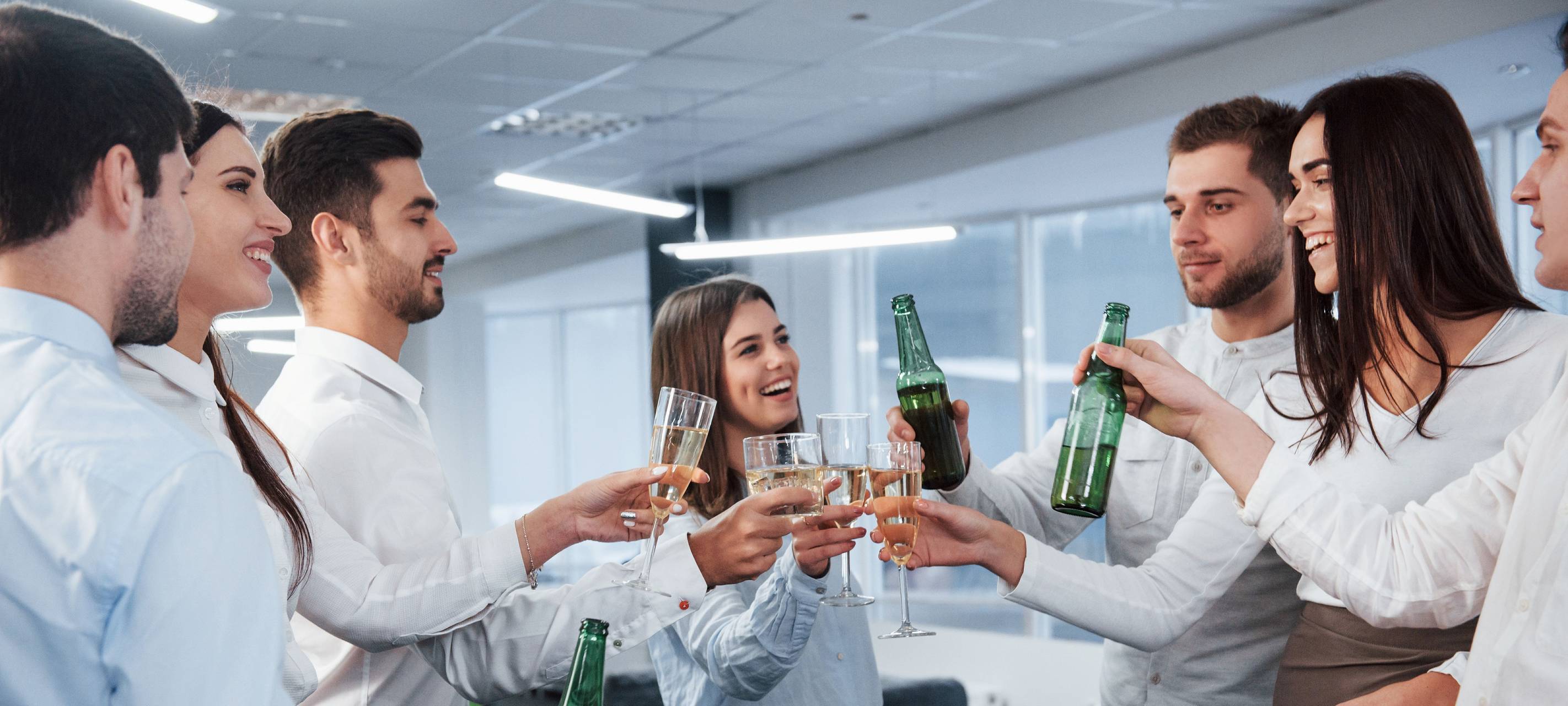 Mehrere Kollegen stoßen im Büro mit Wein an