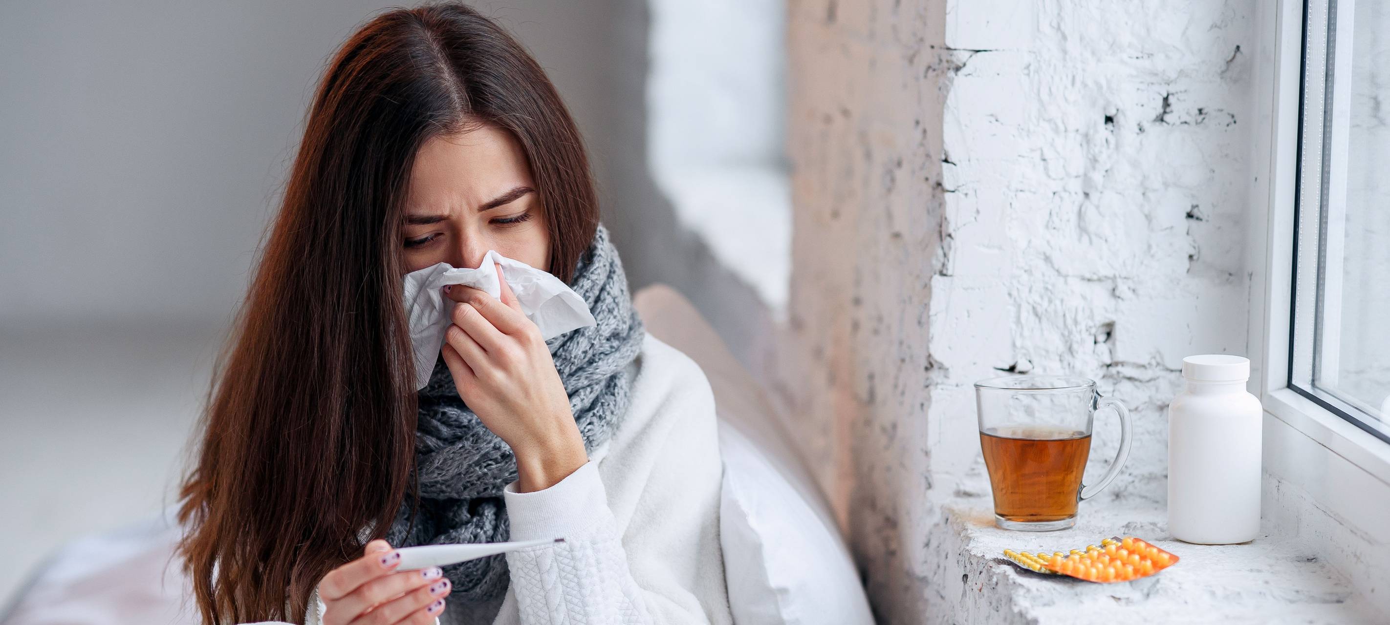 Eine Frau sitzt krank im Bett.