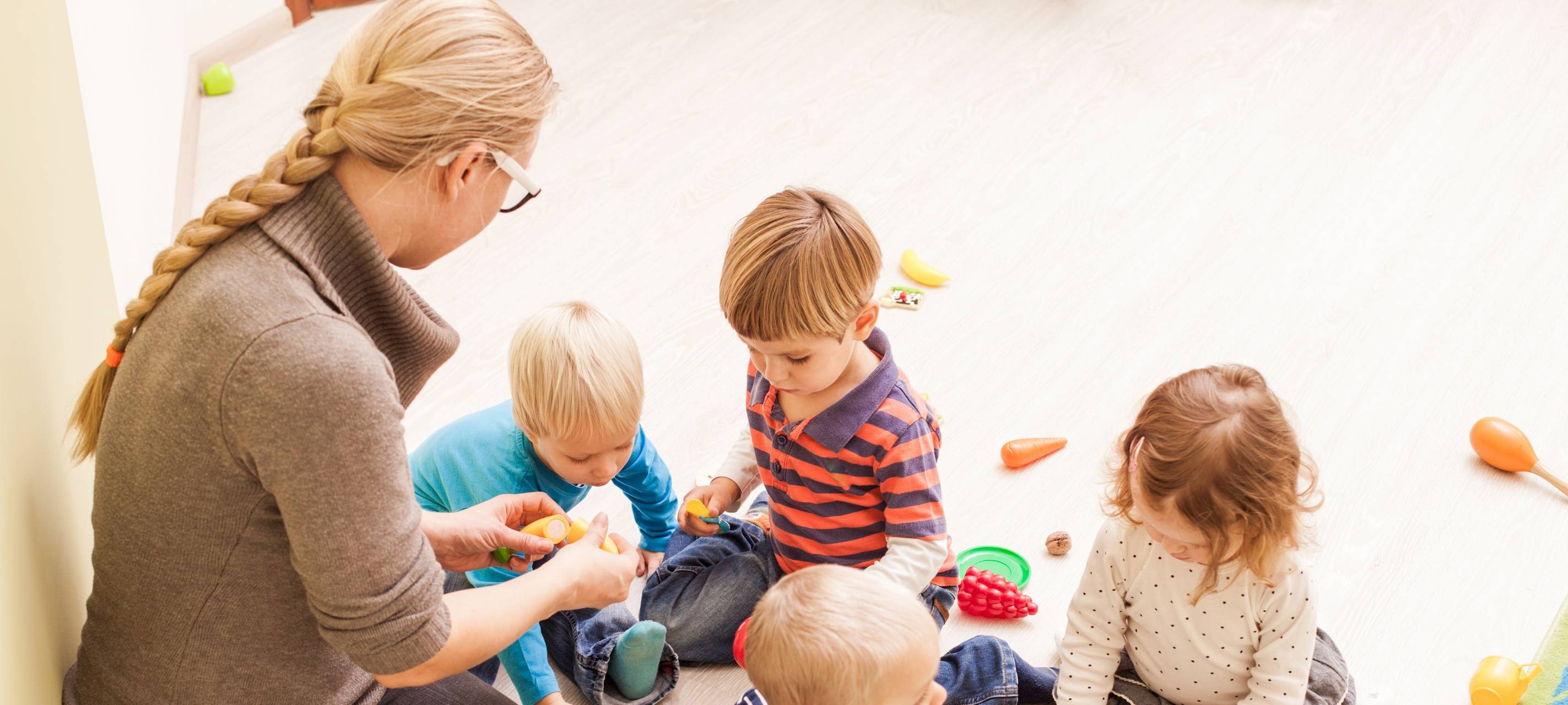 Eine frau spielt mit vier kleinen Kindern