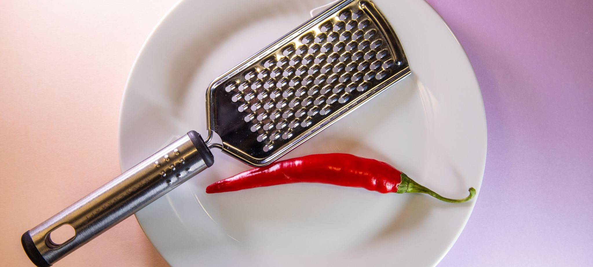 Chilischote liegt neben einer Küchenreibe